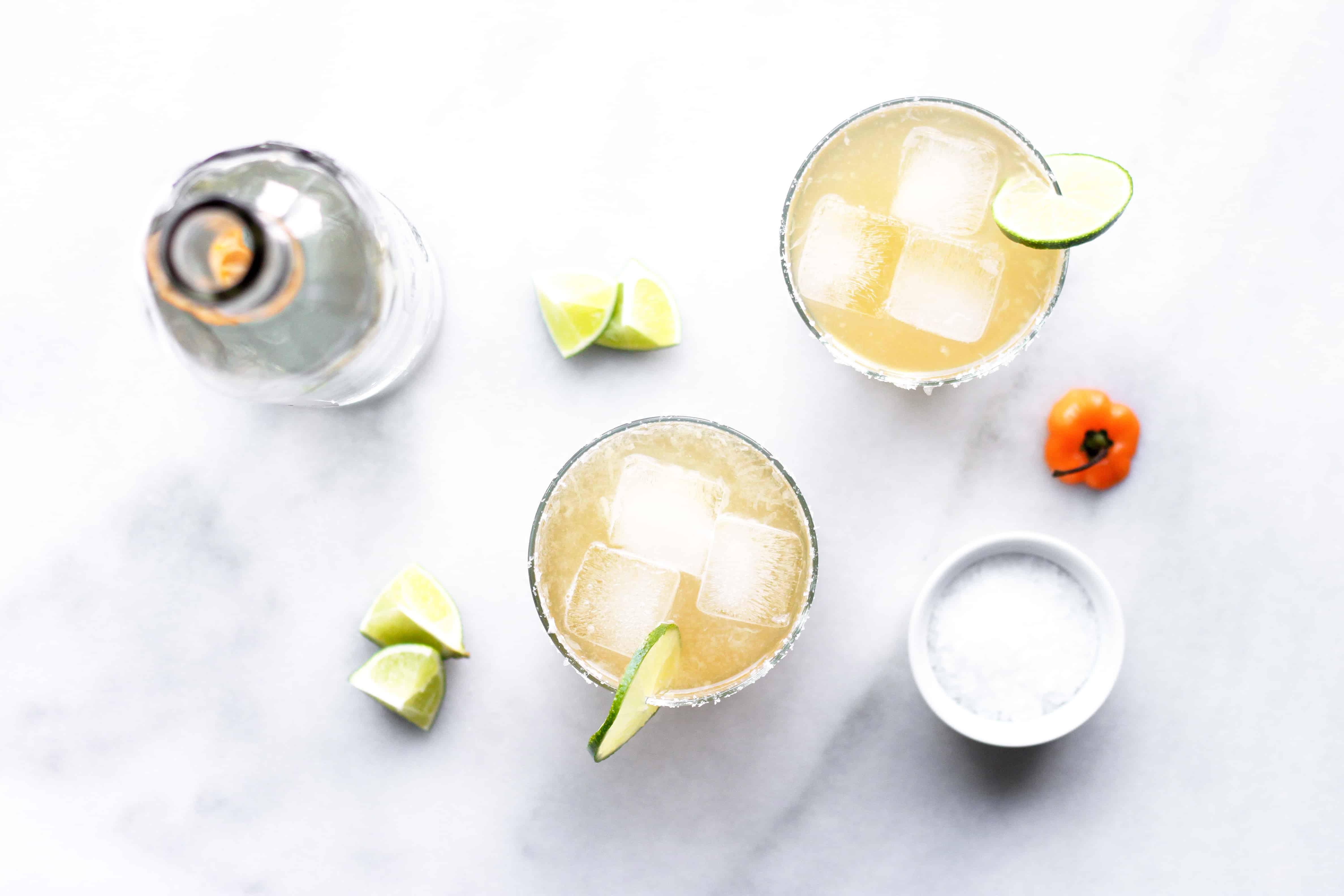 Spicy Habanero ginger beer margarita in glass with ice, lime, salted rim and bottle of tequila